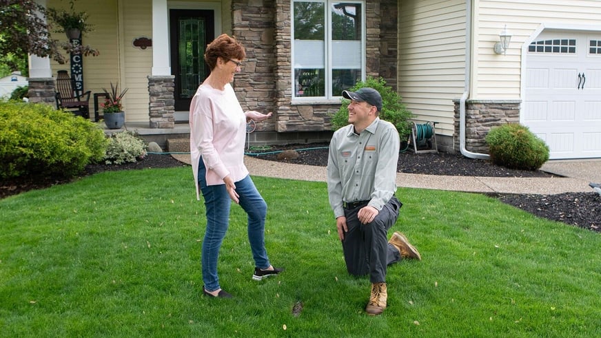 technician looking at lawn with customer