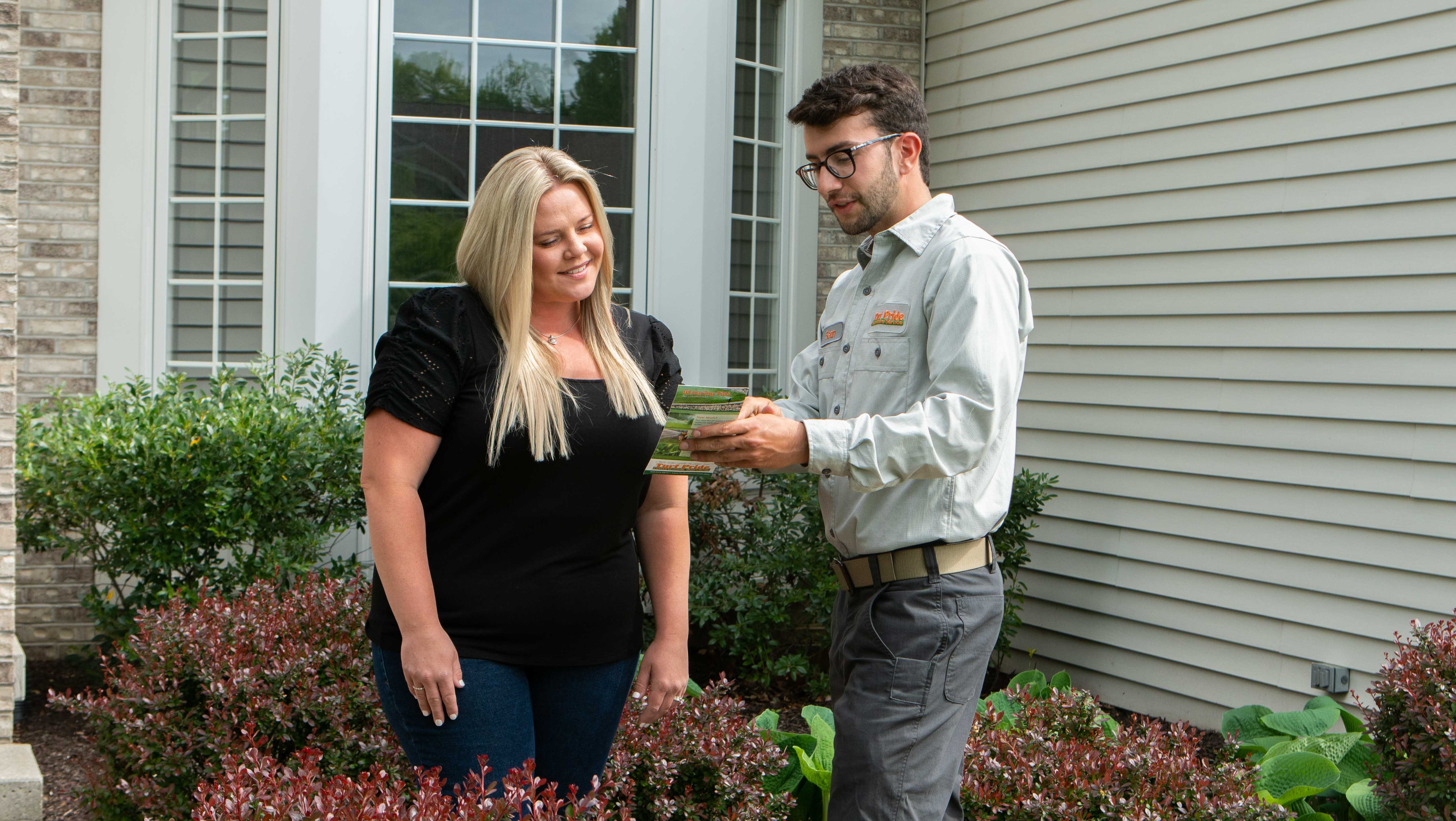 technician talking to customer in front lawn