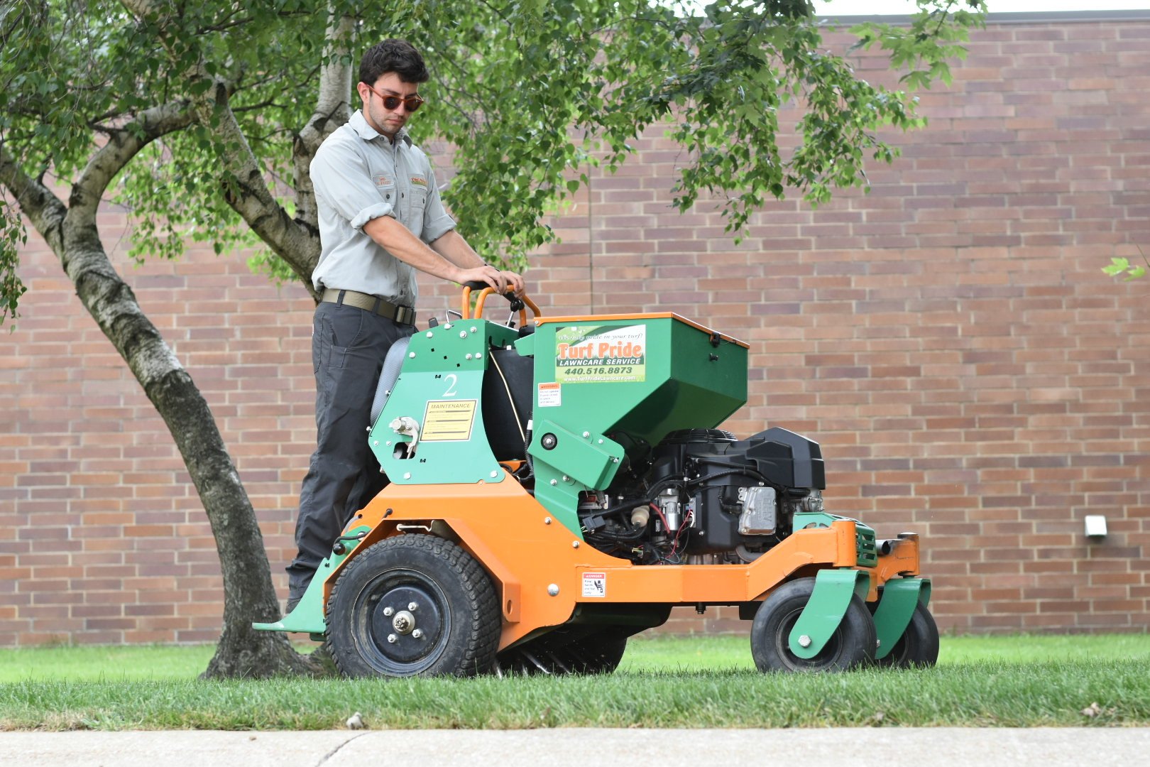 team member on machine aerating green lawn 1