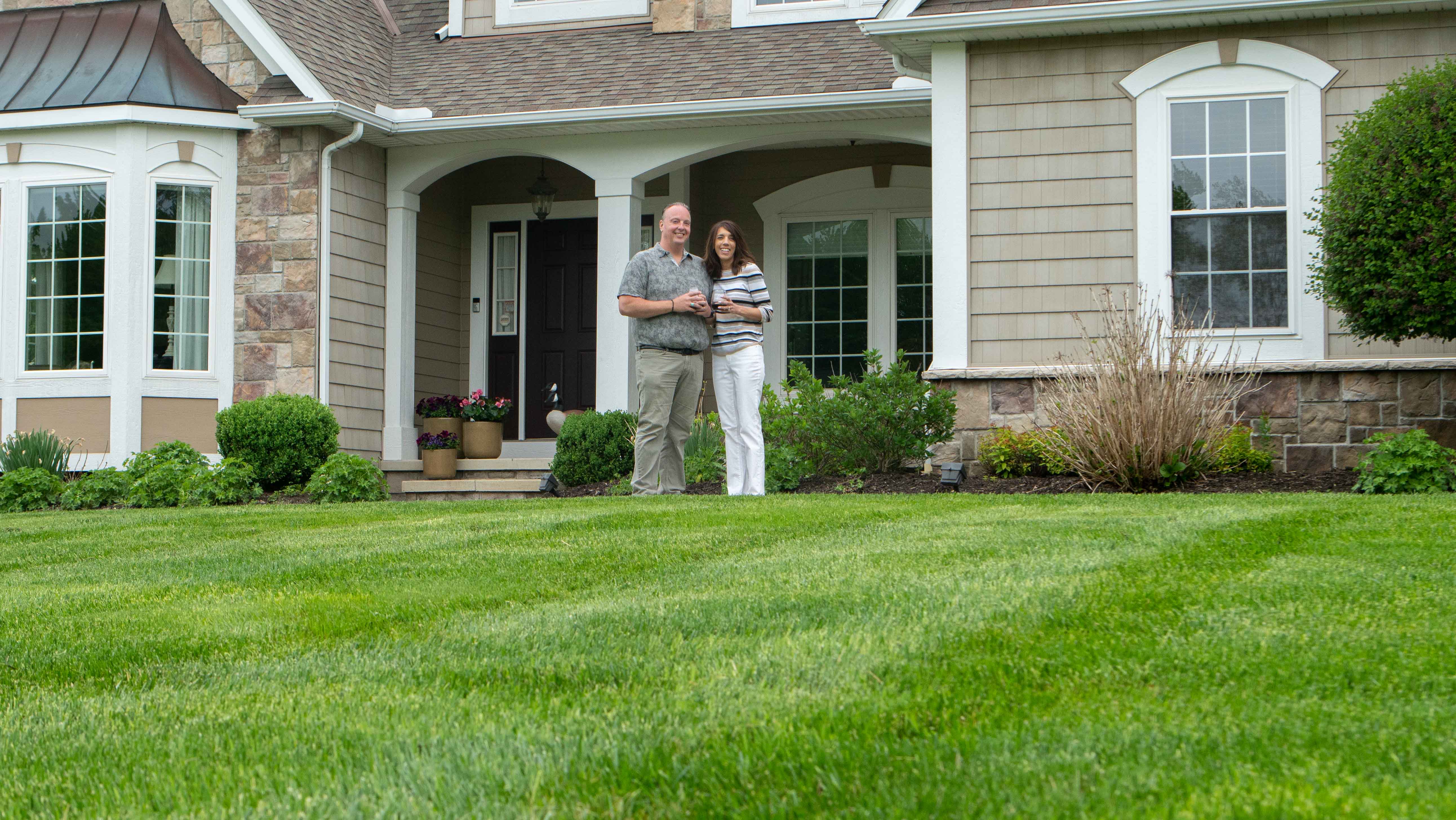 couple standing on their green lawn 